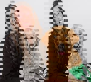 A smiling woman next to a golden retriever