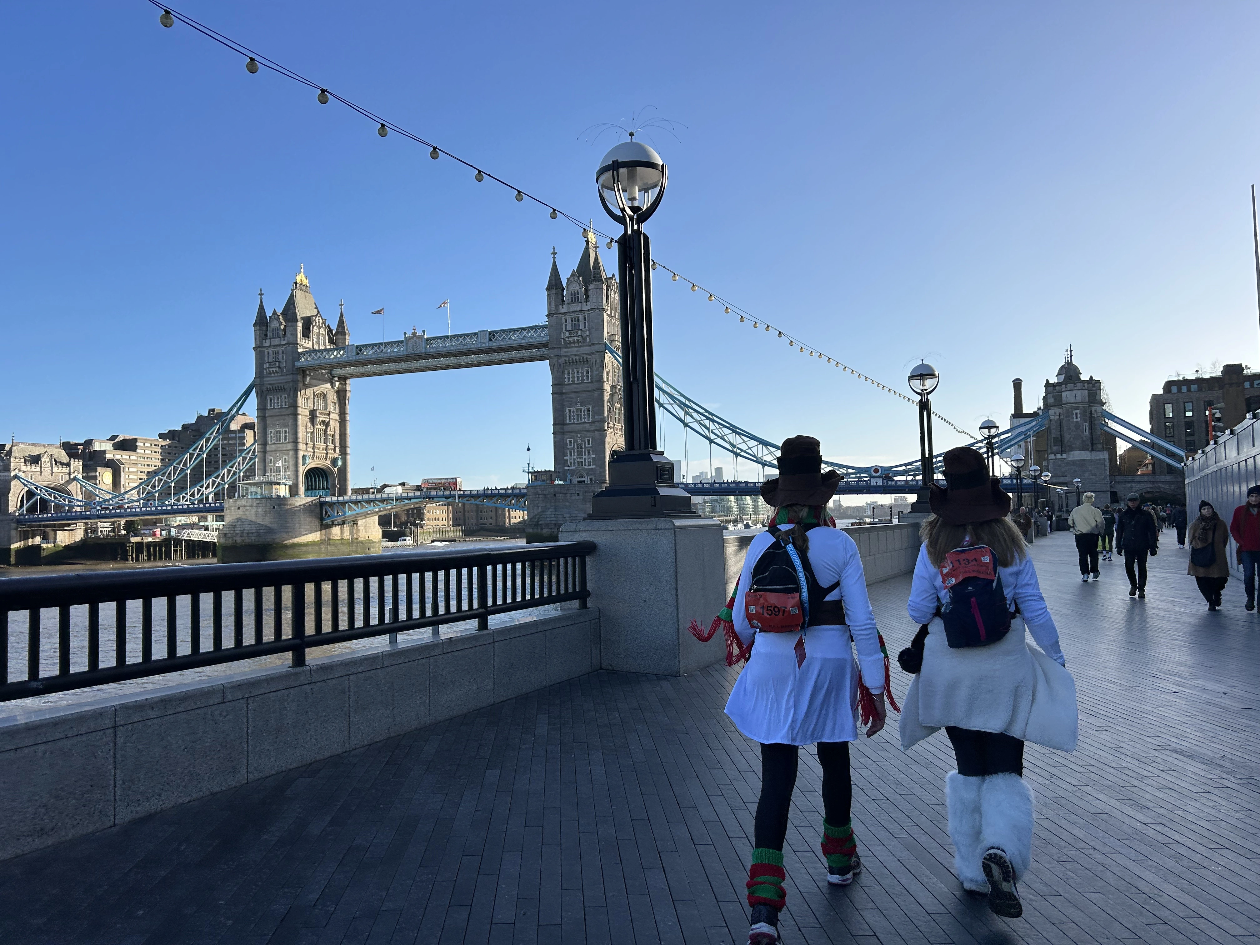 Two London Winter Walk participants walking along the Thames past Tower Bridge in London. 