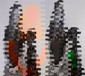 A woman sitting next to a labrador