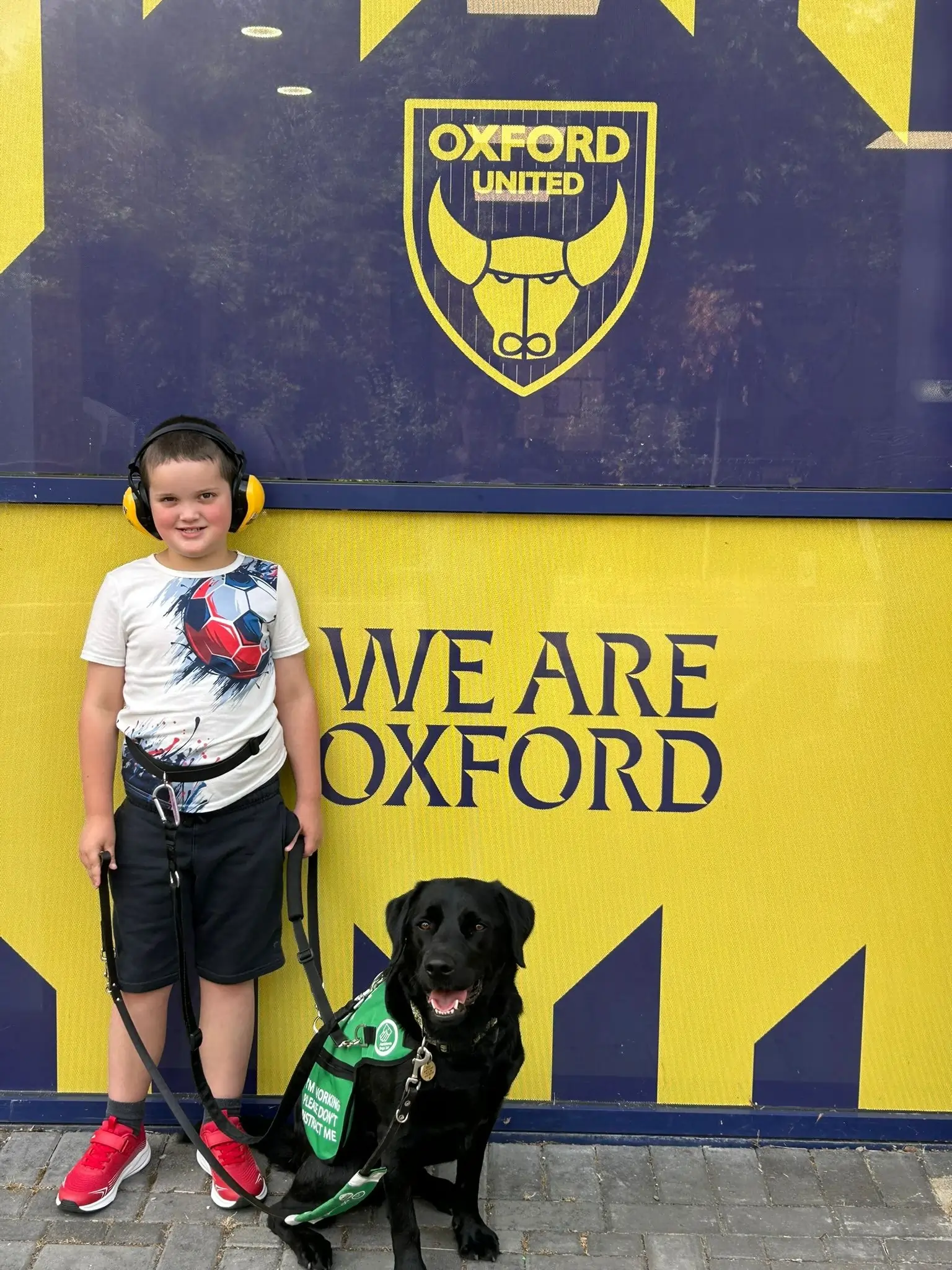 Reco And Jenson Stood In Front Of A We Are Oxford Sign At Oxford Football Stadium